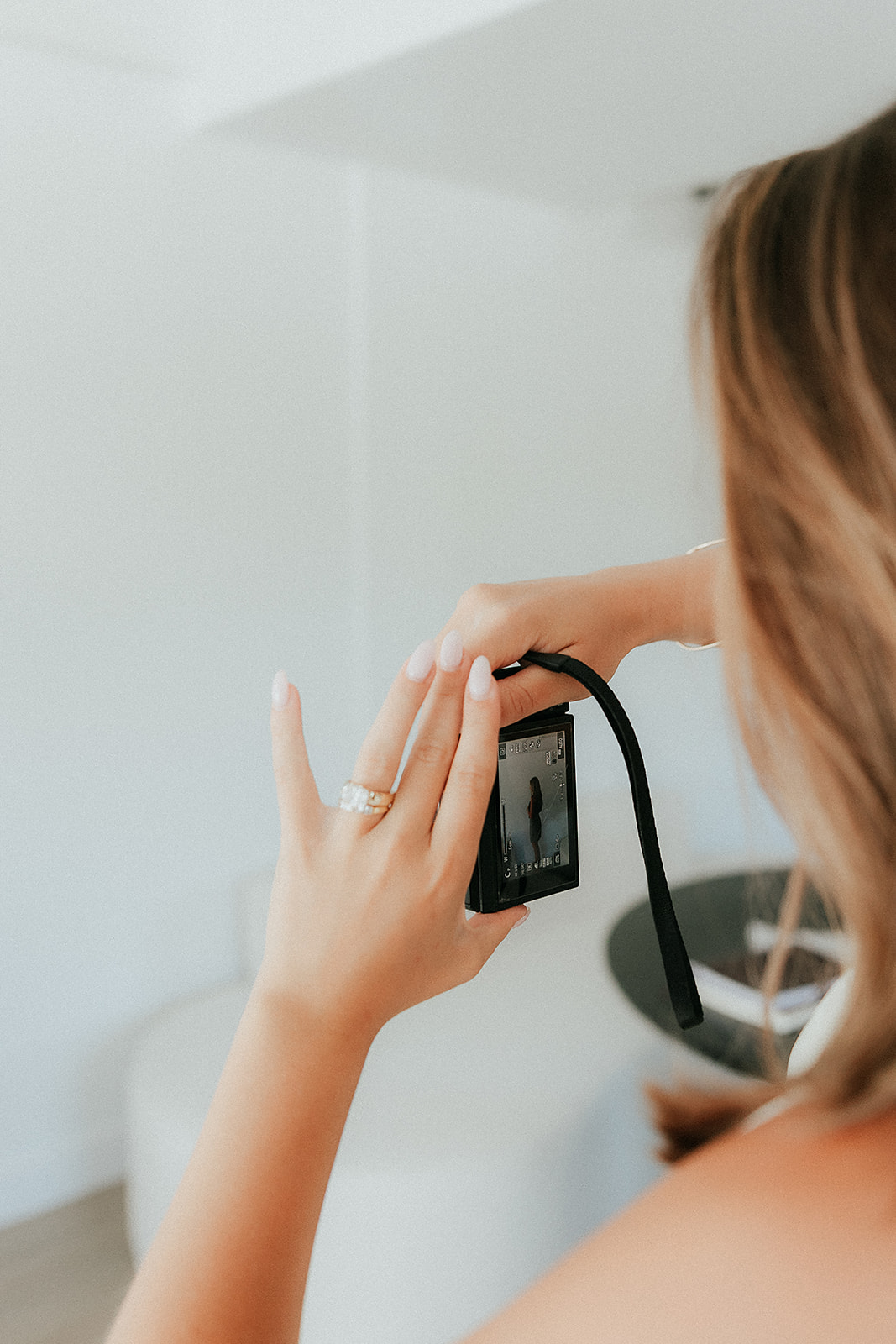 A woman reviewing a photo on a compact camera screen in a bright minimal space
