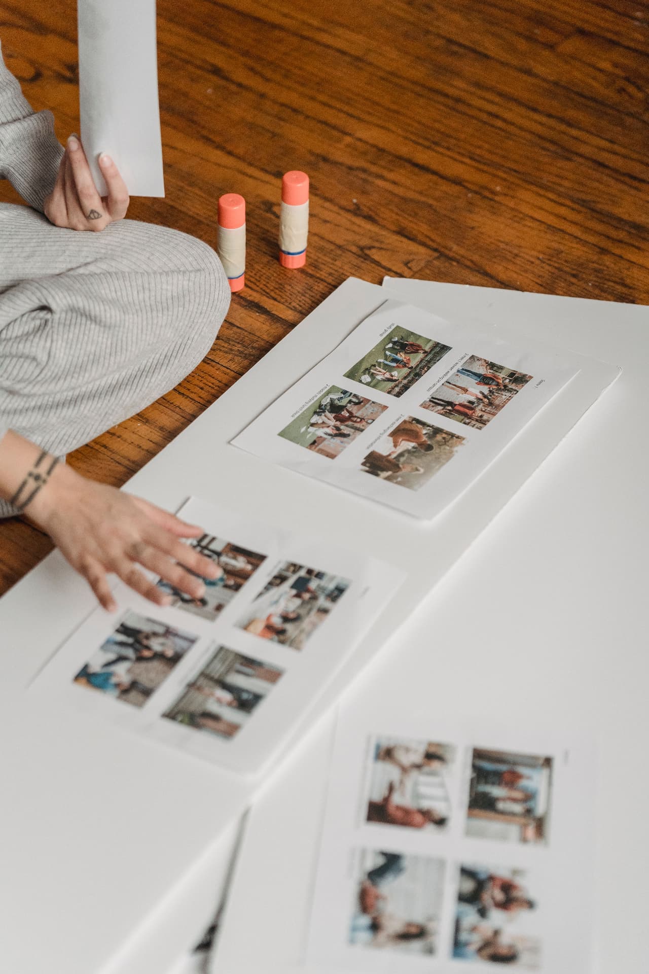 Hands arranging printed photos and moodboard clippings on paper with glue sticks nearby